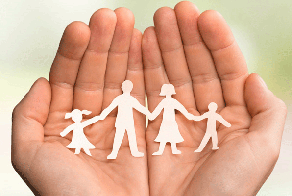Mains tenant un papier découpé représentant une famille